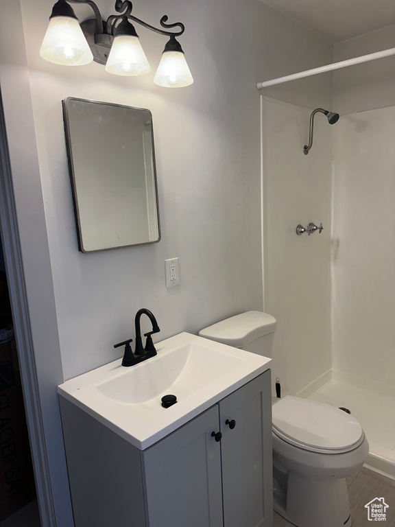 Bathroom with a shower stall, wood finished floors, toilet, and vanity