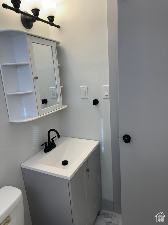 Half bathroom with marble finish floor, toilet, and vanity