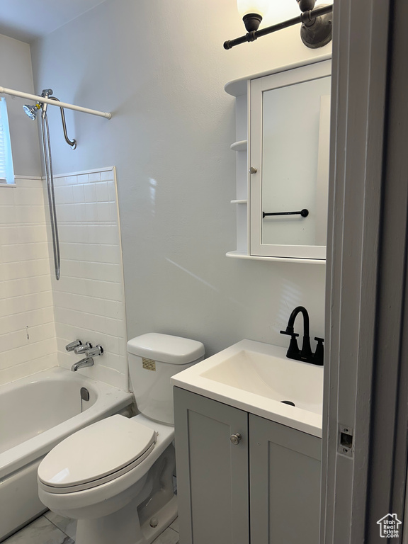 Full bathroom featuring marble finish floor, toilet, vanity, and shower / tub combination