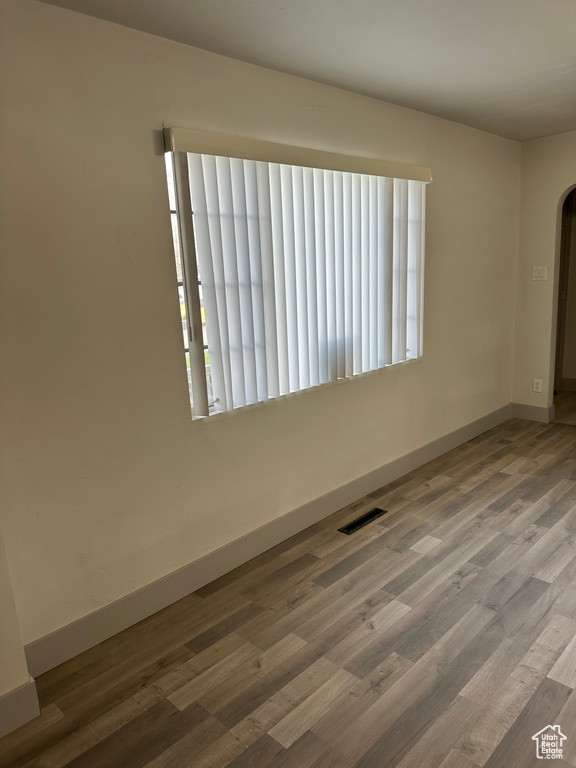 Spare room with baseboards, visible vents, wood finished floors, and arched walkways