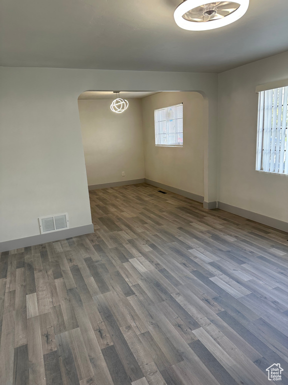 Unfurnished room featuring baseboards, visible vents, wood finished floors, and arched walkways