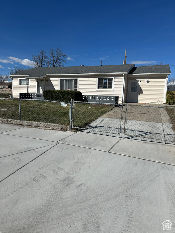 View of front of property with a shingled roof, a fenced front yard, and concrete driveway