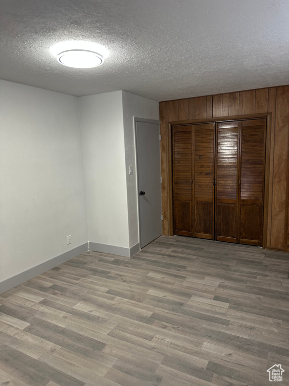 Unfurnished bedroom with baseboards, a closet, light wood-style flooring, and a textured ceiling
