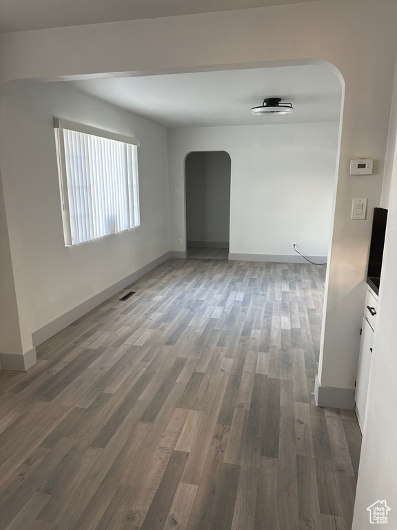 Unfurnished room with baseboards, arched walkways, and dark wood-type flooring