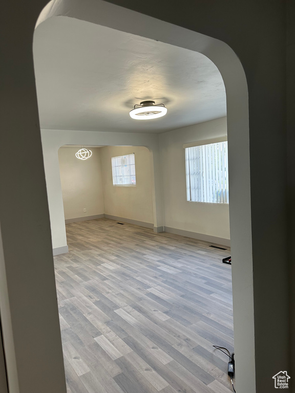 Spare room with visible vents, arched walkways, baseboards, and wood finished floors