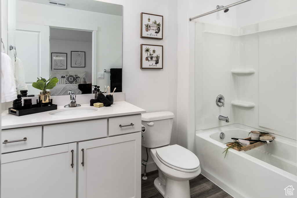 Bathroom with vanity, toilet, tub / shower combination, visible vents, and wood finished floors