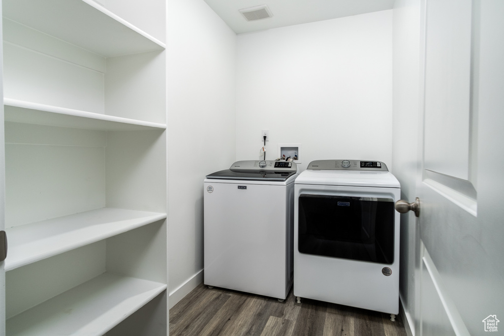 Laundry room featuring separate washer and dryer, dark wood-style flooring, laundry area, and visible vents