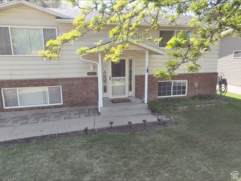 Exterior space featuring brick siding, roof with shingles, and a yard