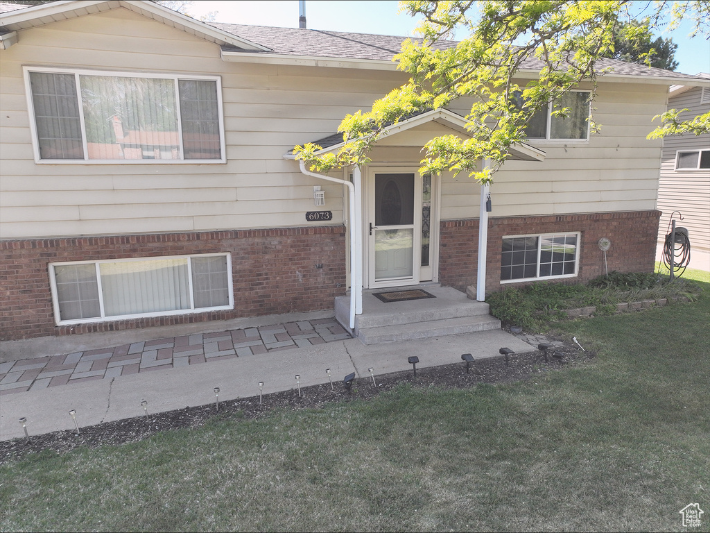 Property entrance with a lawn and brick siding