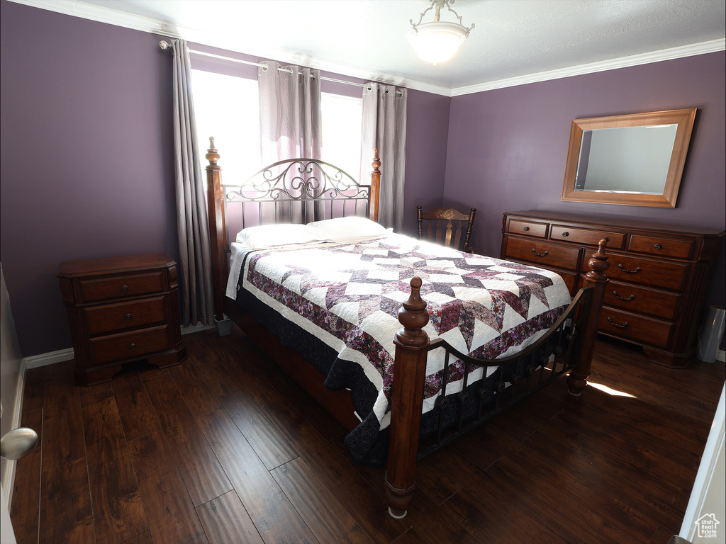 Bedroom with ornamental molding and dark wood finished floors
