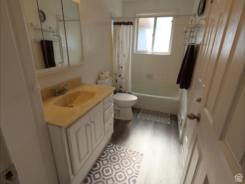 Bathroom with vanity, wood finished floors, shower / bath combo, and toilet