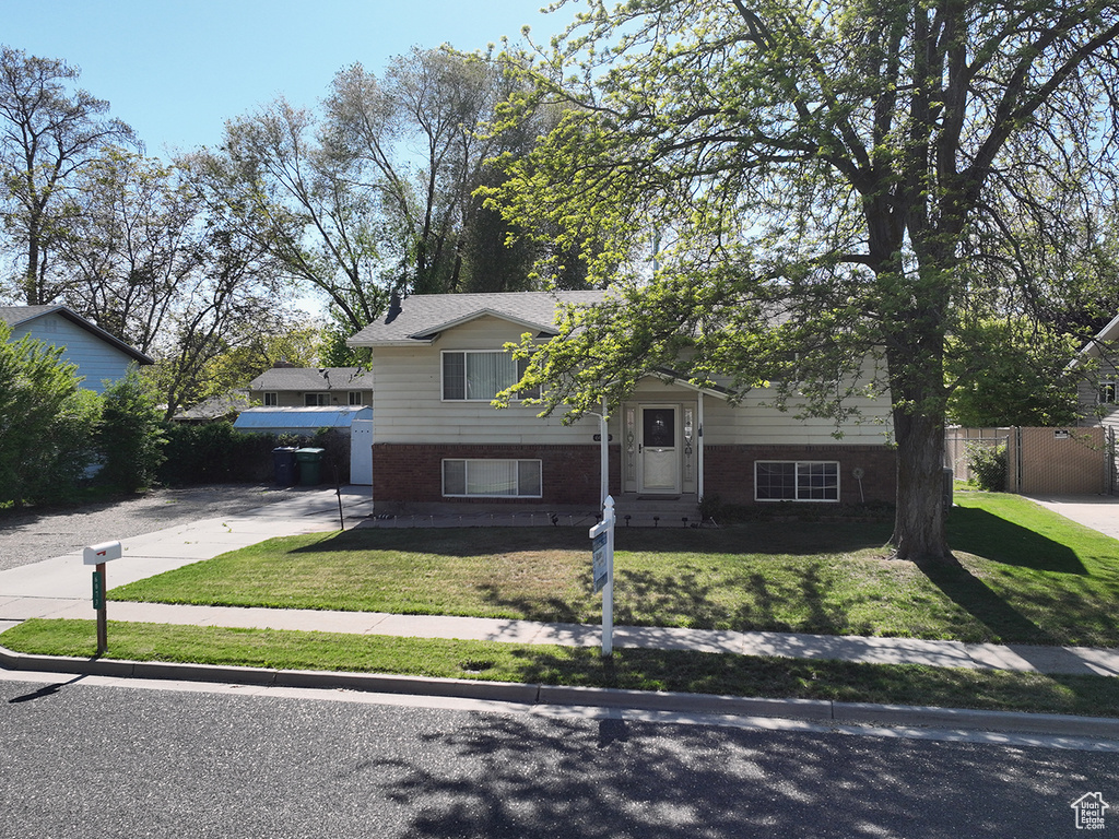 View of front facade featuring fence, a front yard, and brick siding