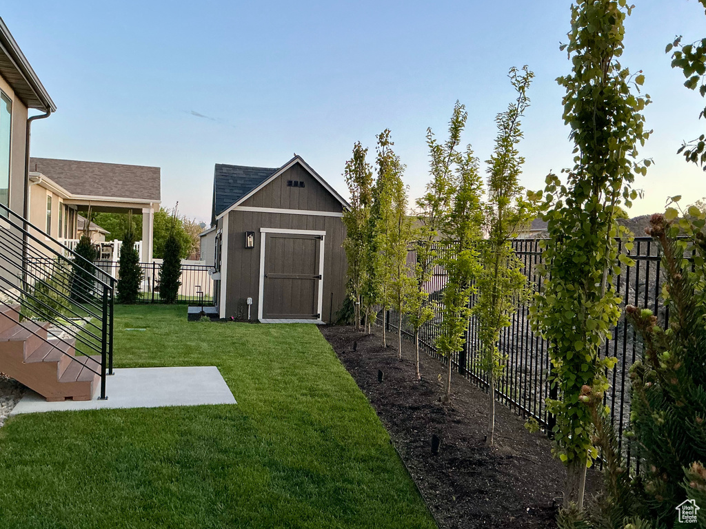 View of yard featuring stairs, a fenced backyard, a shed, and an outbuilding