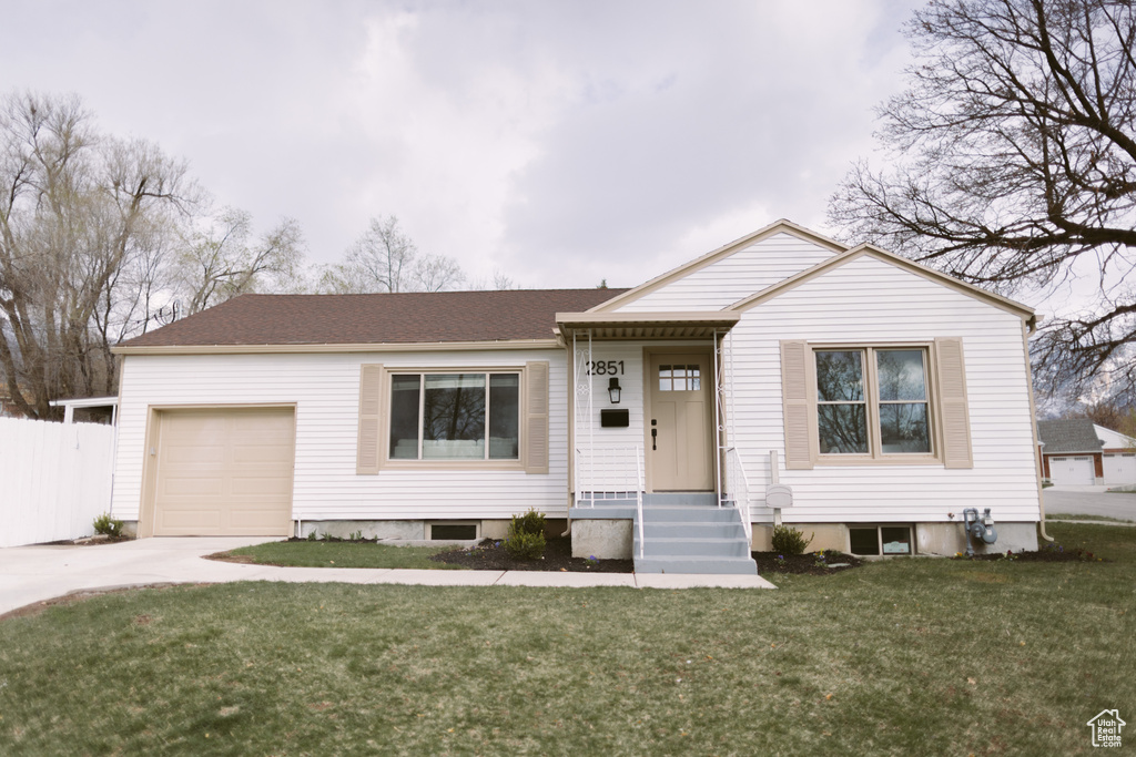 View of front of property with a front yard, a garage, and concrete driveway