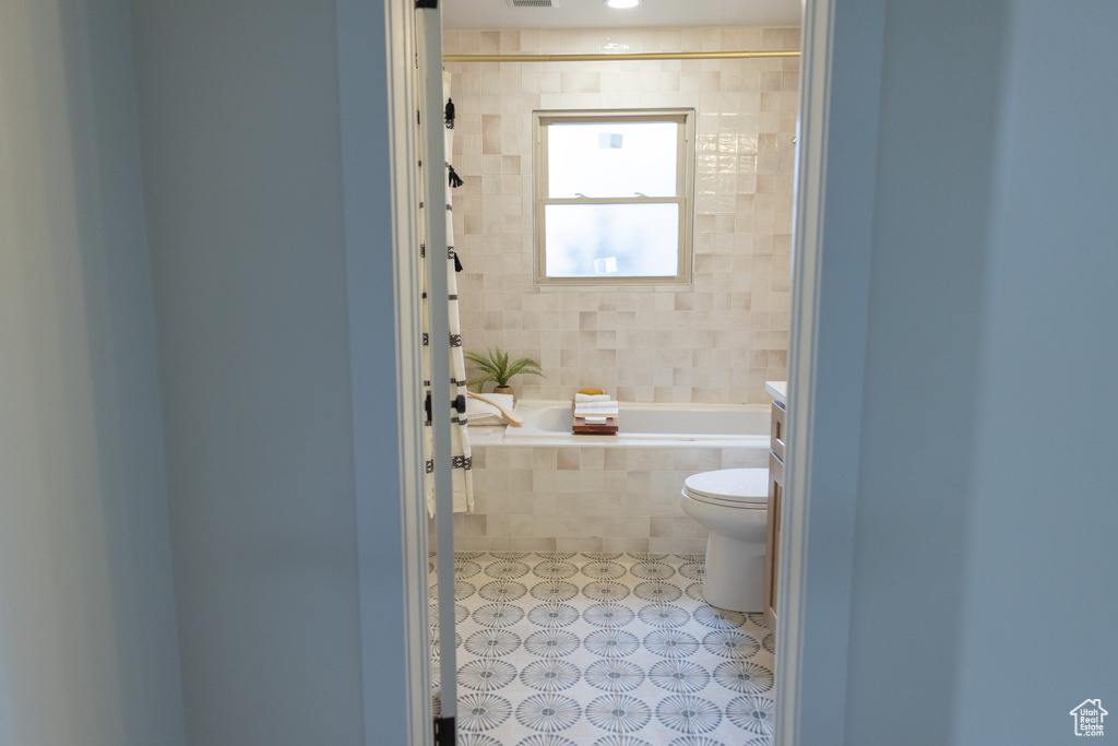 Full bathroom with toilet, tile patterned flooring, and tiled shower / bath