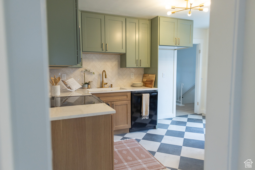 Kitchen featuring dishwasher, green cabinetry, an inviting chandelier, and light floors