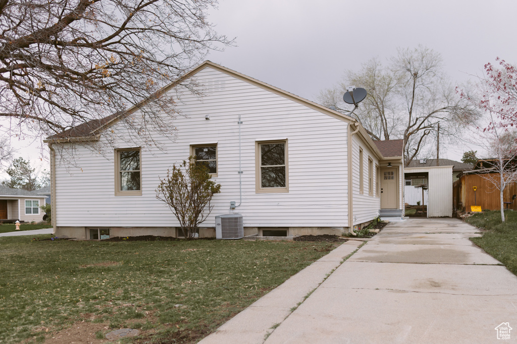 Back of house featuring a lawn, driveway, central AC unit, and entry steps