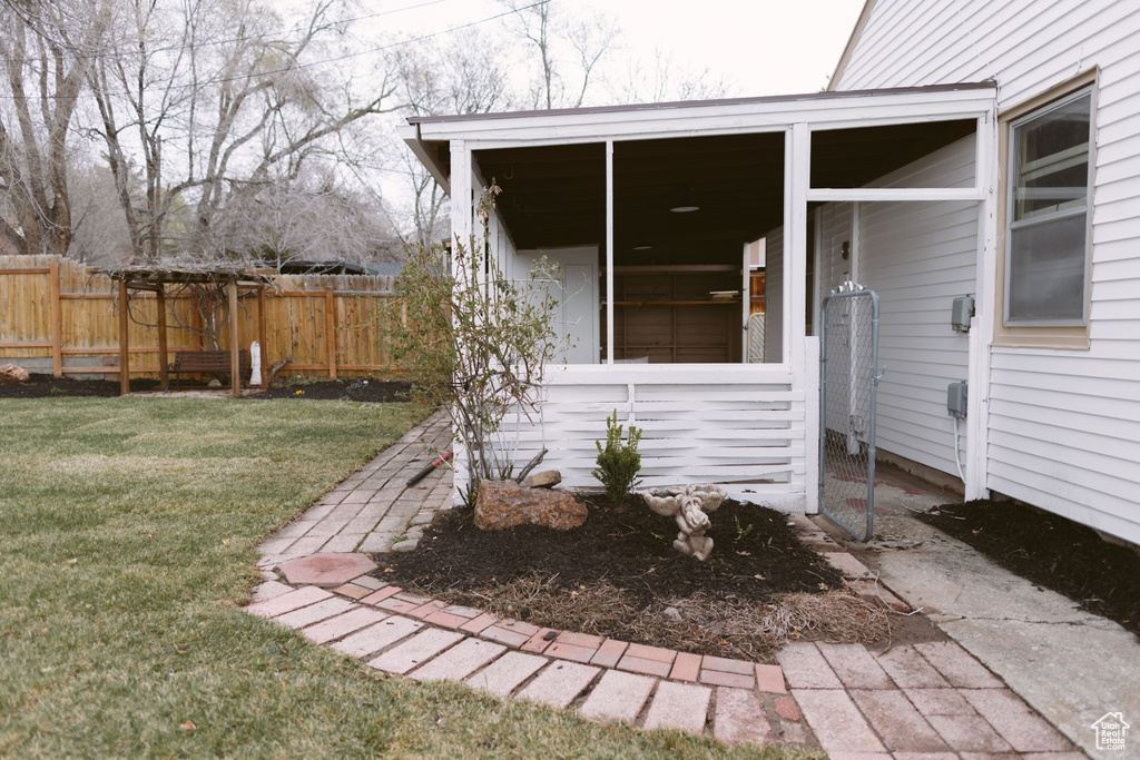View of exterior entry featuring fence and a yard