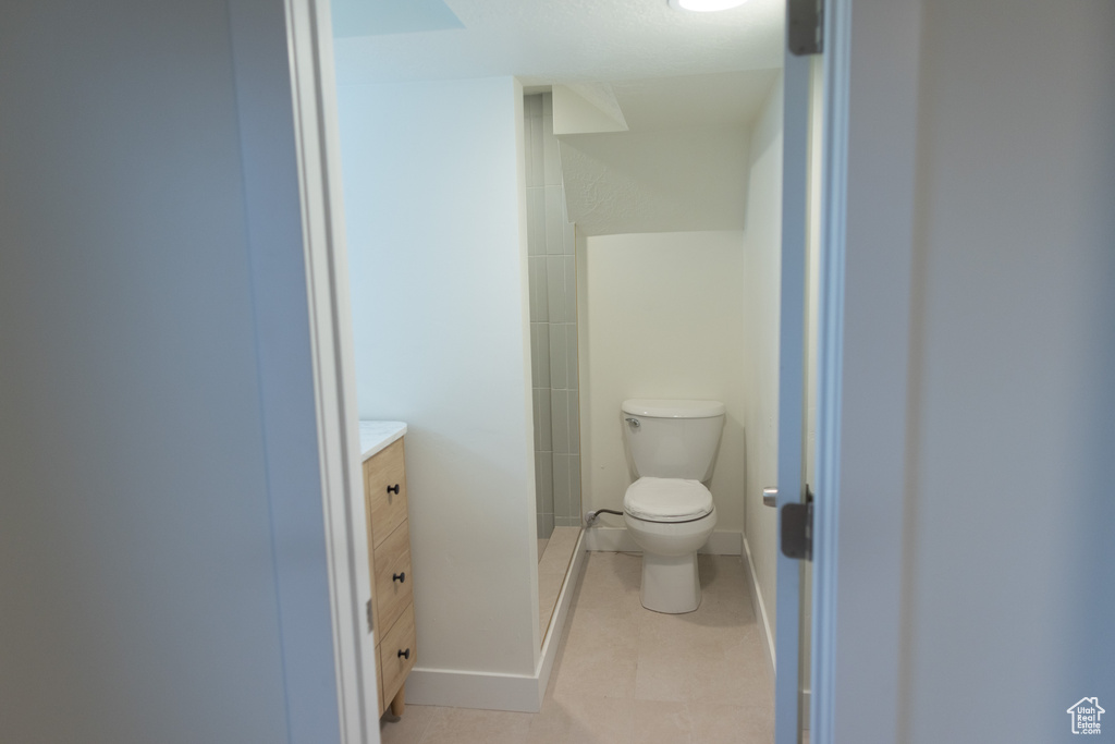 Full bath with a stall shower, tile patterned floors, toilet, vanity, and baseboards