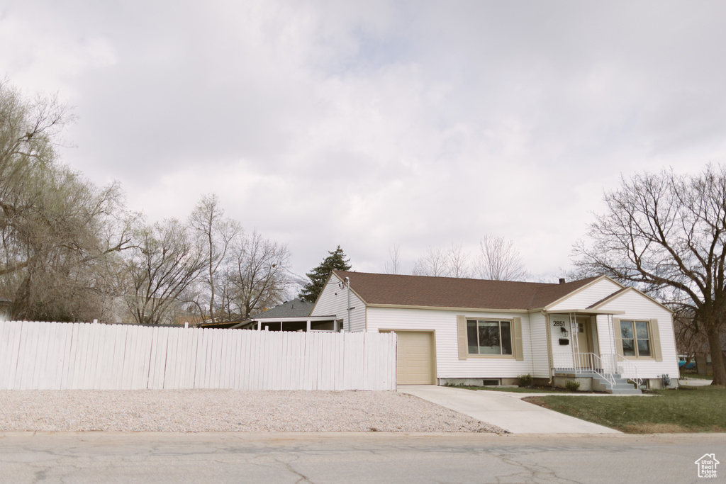 View of front of home featuring a garage, fence, and concrete driveway