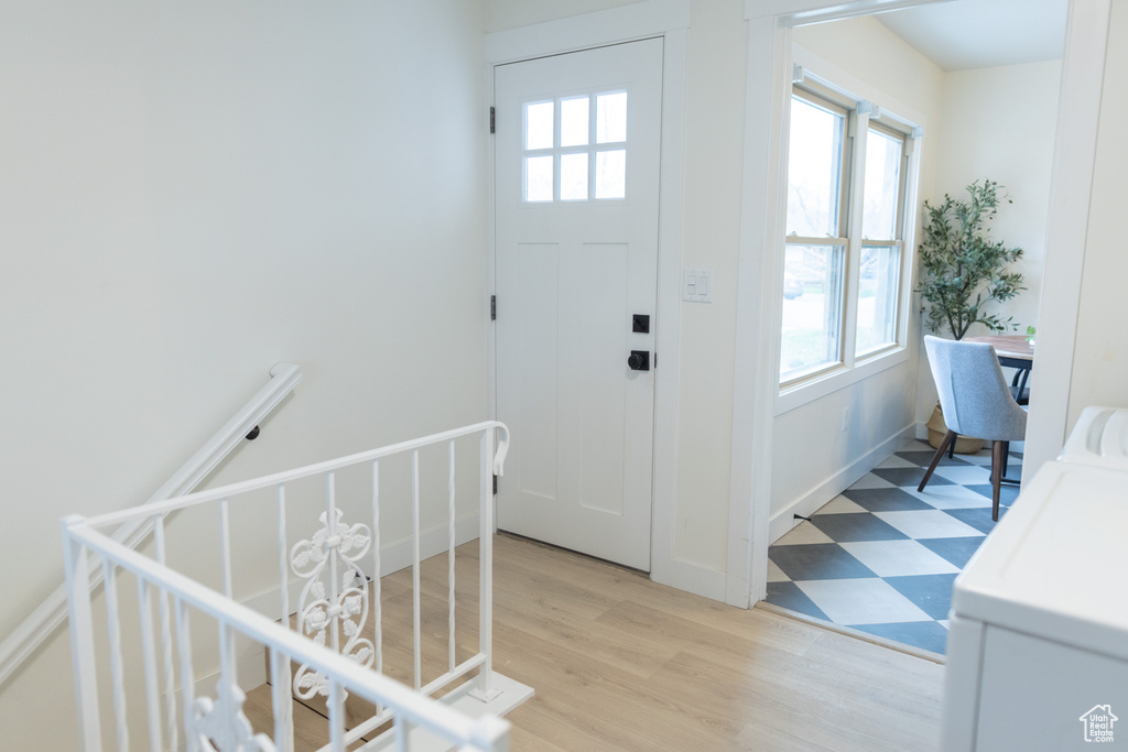 Foyer entrance featuring baseboards, washing machine and dryer, and light floors