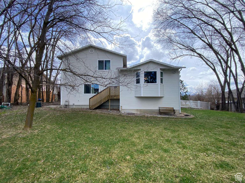 Rear view of property featuring fence and a yard
