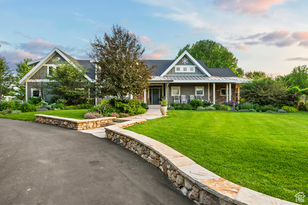 View of front of home featuring a standing seam roof, a porch, a yard, and a metal roof