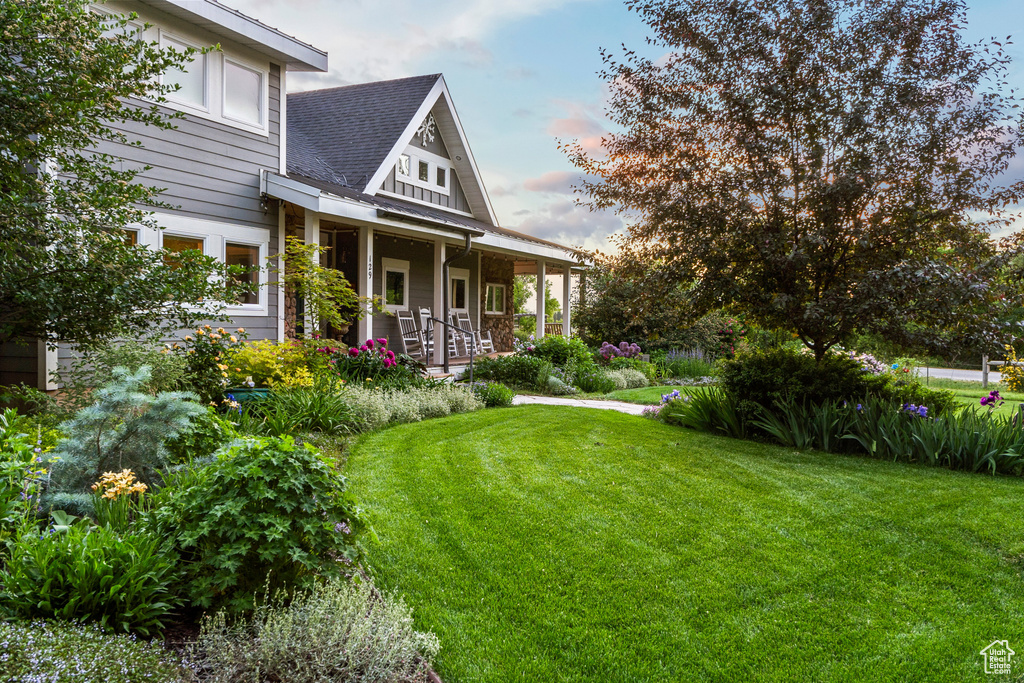 Yard at dusk with covered porch and a lawn