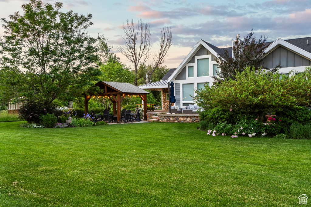 View of grassy yard with a gazebo and a patio area