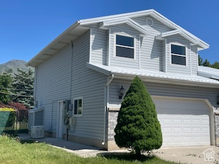 View of property exterior featuring a garage, concrete driveway, and central air condition unit