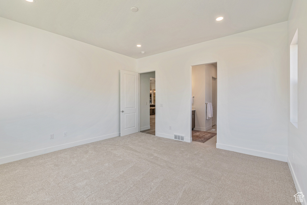Unfurnished bedroom with recessed lighting, baseboards, carpet floors, visible vents, and ensuite bathroom