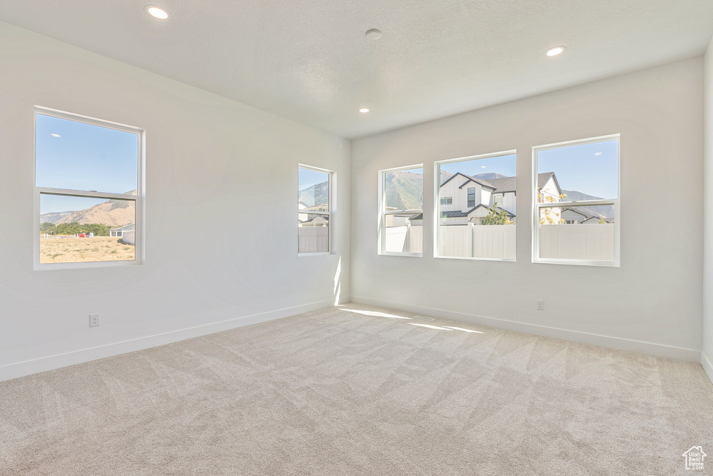Empty room featuring baseboards, recessed lighting, and light colored carpet