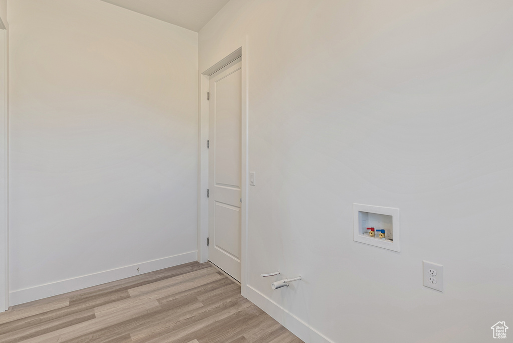 Laundry area featuring baseboards, light wood-type flooring, washer hookup, and laundry area
