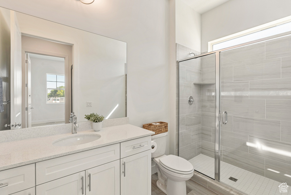 Full bathroom featuring a stall shower, toilet, and vanity