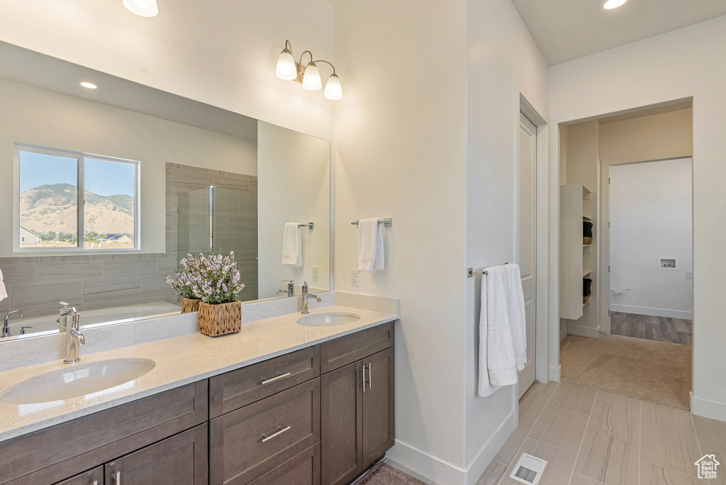 Full bath featuring a sink, double vanity, visible vents, and baseboards