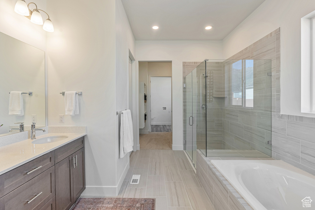 Full bathroom featuring vanity, recessed lighting, baseboards, a stall shower, and a bath