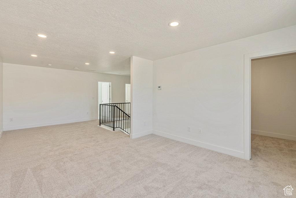 Spare room with recessed lighting, baseboards, light colored carpet, and a textured ceiling