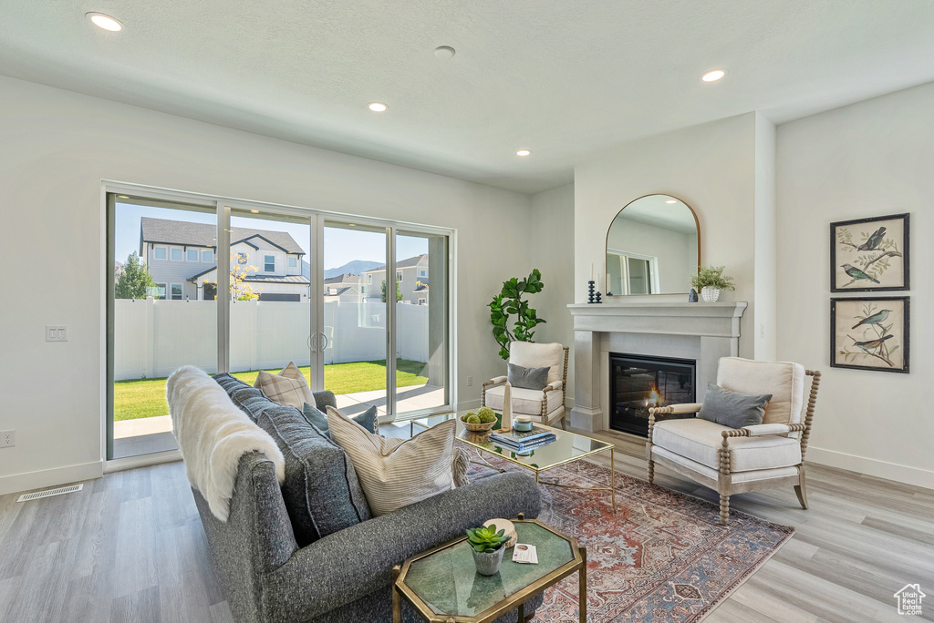 Living area with recessed lighting, a glass covered fireplace, baseboards, and wood finished floors