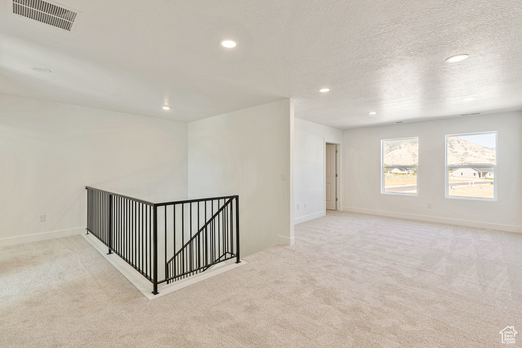 Spare room with carpet, a textured ceiling, baseboards, visible vents, and recessed lighting