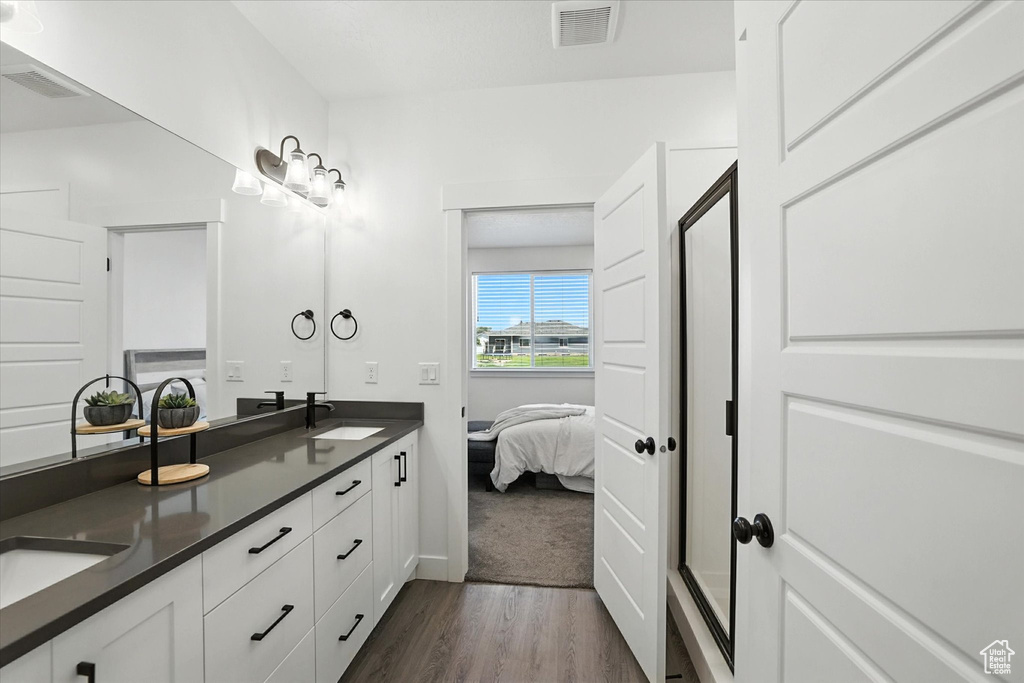 Ensuite bathroom with wood finished floors, double vanity, and a shower stall