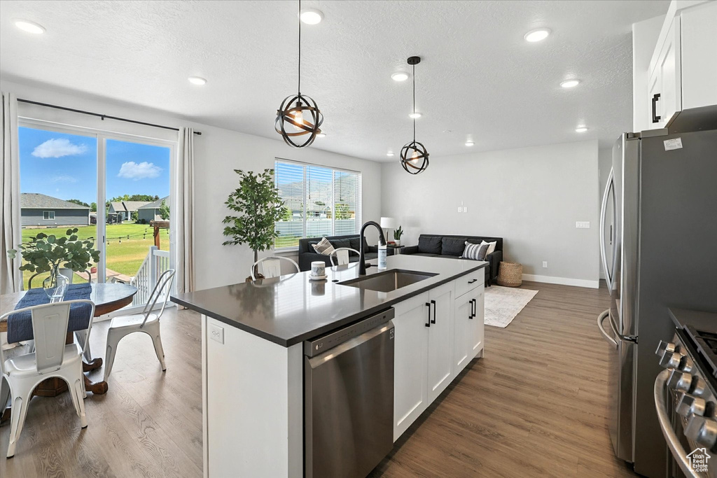 Kitchen featuring appliances with stainless steel finishes, open floor plan, dark countertops, dark wood-type flooring, and recessed lighting