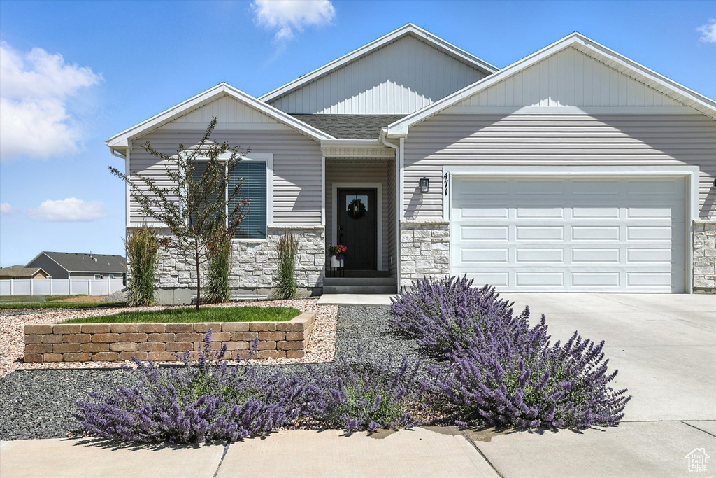 Craftsman house featuring stone siding, an attached garage, and driveway