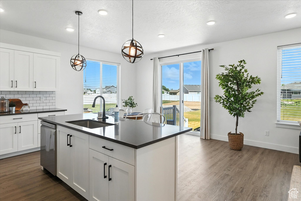 Kitchen featuring dark countertops, dark wood-style floors, dishwasher, backsplash, and recessed lighting
