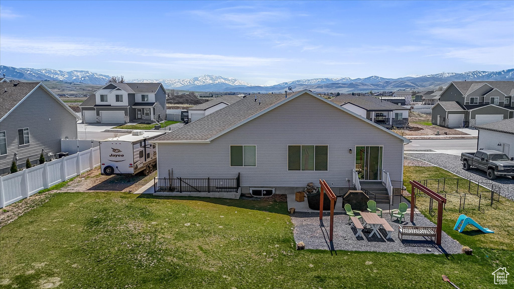 Rear view of house featuring a mountain view, a fenced backyard, and a residential view