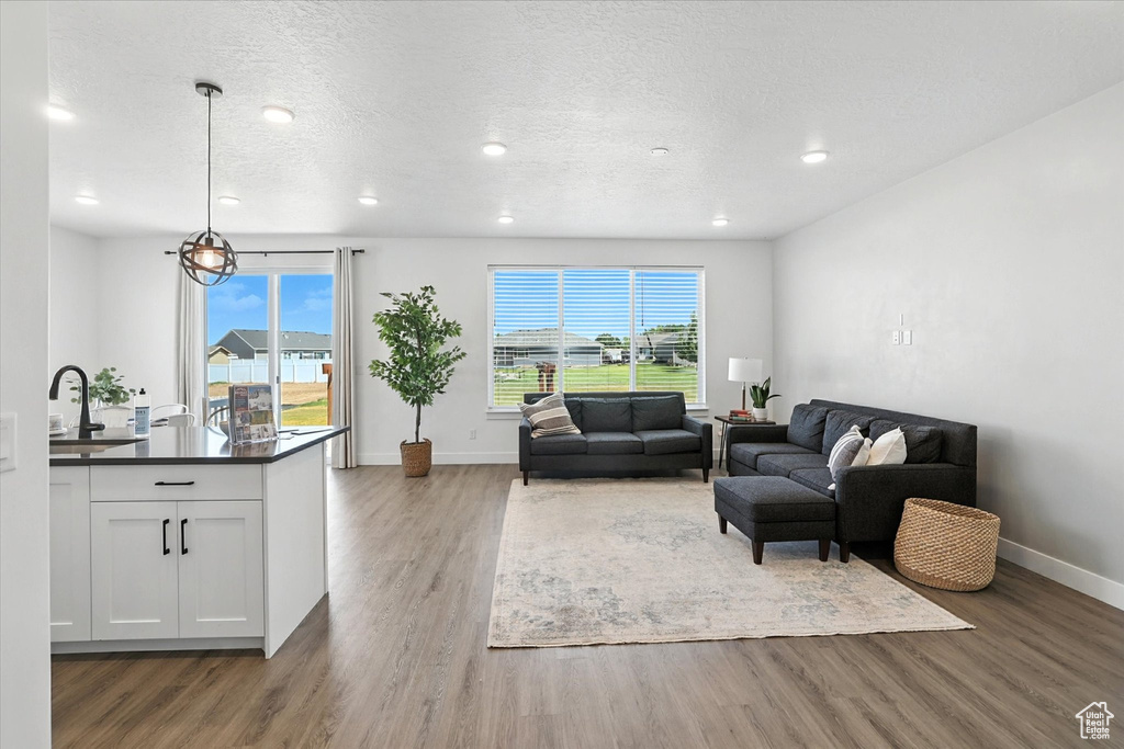 Living room with wood finished floors, plenty of natural light, recessed lighting, and a textured ceiling