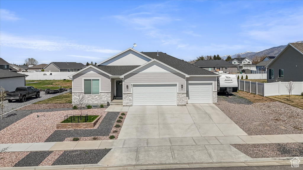 View of front of property featuring a garage, a residential view, driveway, and stone siding