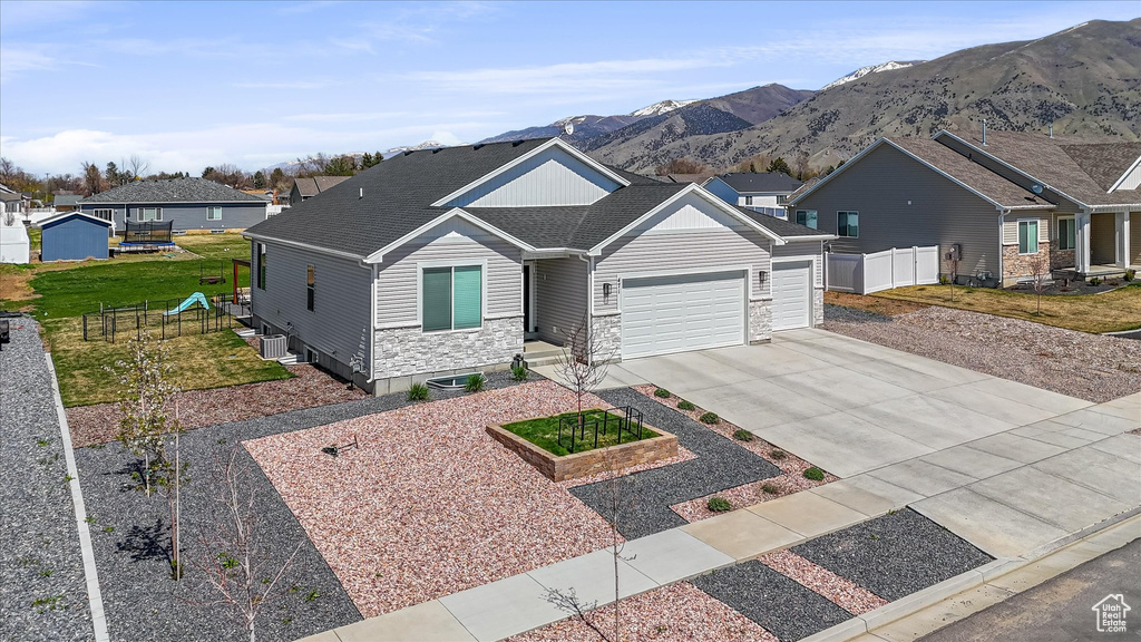 Craftsman inspired home featuring a garage, stone siding, a residential view, driveway, and a mountain view