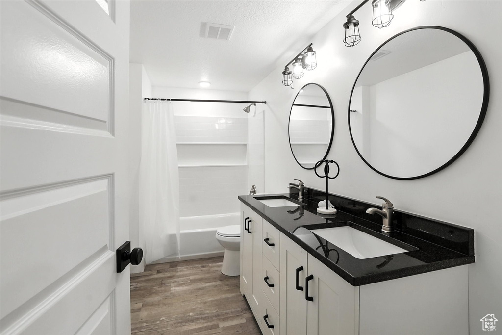Full bathroom featuring shower / tub combo with curtain, double vanity, and wood finished floors