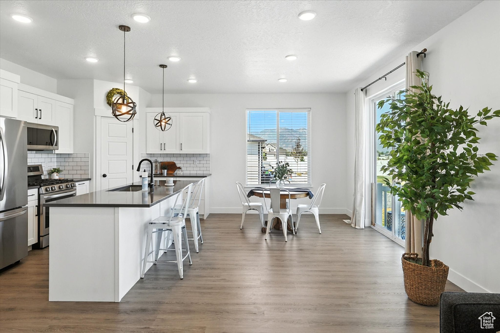 Kitchen with appliances with stainless steel finishes, dark countertops, tasteful backsplash, a kitchen bar, and recessed lighting