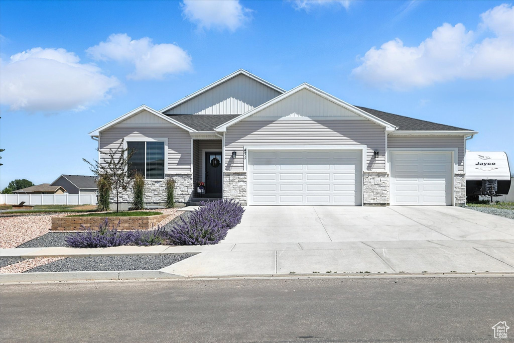 Craftsman-style house featuring a garage, stone siding, and concrete driveway